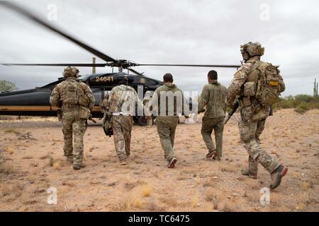 Us Border Patrol escort eine Gruppe illegaler Migranten zu einem Blackhawk Hubschrauber, nachdem sie festgenommen wurden, Kreuzung aus Mexiko auf der Tohono O'odham Indian Reservation 22. Mai 2019 in der Nähe von Pisinemo, Arizona. Die Gesichter sind verdeckt durch die Border Patrol, um ihre Identität zu schützen. Stockfoto