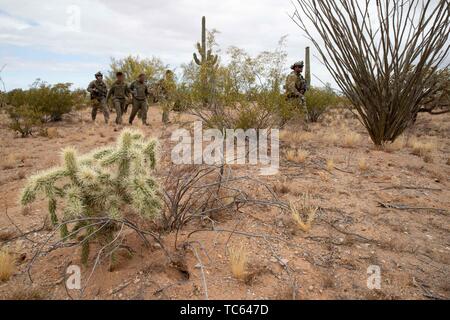 Us Border Patrol escort eine Gruppe illegaler Migranten zu einem Blackhawk Hubschrauber, nachdem sie festgenommen wurden, Kreuzung aus Mexiko auf der Tohono O'odham Indian Reservation 22. Mai 2019 in der Nähe von Pisinemo, Arizona. Die Gesichter sind verdeckt durch die Border Patrol, um ihre Identität zu schützen. Stockfoto