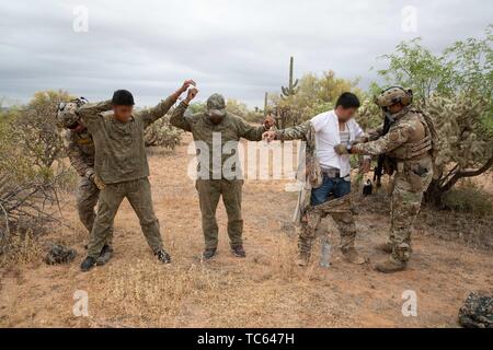 Us Border Patrol Suche eine Gruppe von illegalen Migranten, nachdem sie festgenommen wurden, Kreuzung aus Mexiko auf der Tohono O'odham Indian Reservation 22. Mai 2019 in der Nähe von Pisinemo, Arizona. Die Gesichter sind verdeckt durch die Border Patrol, um ihre Identität zu schützen. Stockfoto