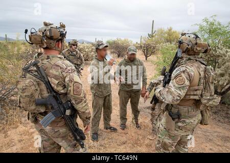 Us Border Patrol stellen Wasser auf eine Gruppe von illegalen Migranten, nachdem sie festgenommen wurden, Kreuzung aus Mexiko auf der Tohono O'odham Indian Reservation 22. Mai 2019 in der Nähe von Pisinemo, Arizona. Die Gesichter sind verdeckt durch die Border Patrol, um ihre Identität zu schützen. Stockfoto