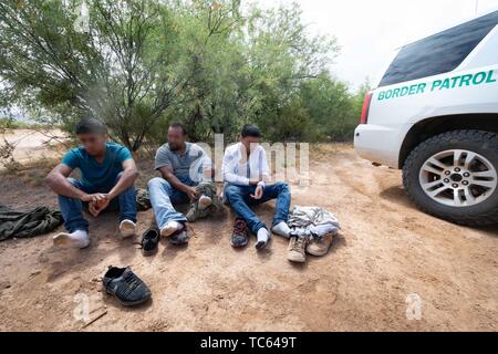 Us Border Patrol-Agenten festzunehmen eine Gruppe von illegalen Migranten, nachdem sie aus Mexiko auf der Tohono O'odham Indian Reservation 22. Mai 2019 in der Nähe von Pisinemo, Arizona durchquert. Die Gesichter sind verdeckt durch die Border Patrol, um ihre Identität zu schützen. Stockfoto