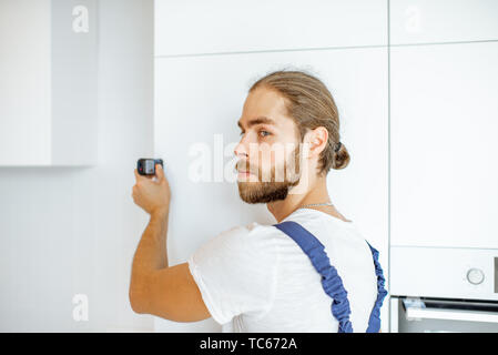 Heimwerker Messen von Distanzen mit elektronischer Messung Werkzeug in der Küche während der Renovierung Stockfoto