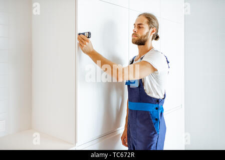 Heimwerker Messen von Distanzen mit elektronischer Messung Werkzeug in der Küche während der Renovierung Stockfoto