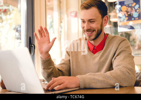 Freelancer fröhlich winkende Hand, während mit Videokonferenz auf Laptop Stockfoto