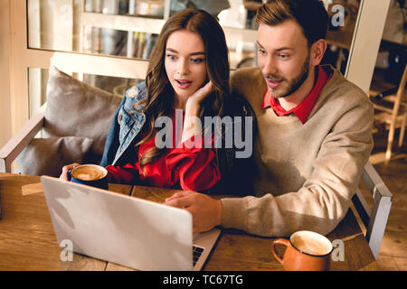 Überrascht Mann, schöne junge Frau mit Laptop im Cafe Stockfoto