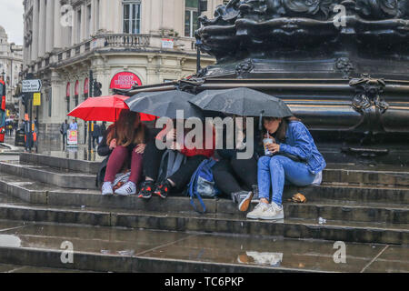 London, Großbritannien. 6. Juni, 2019. Die Menschen drängten sich unter Sonnenschirmen auf den Stufen des Eros Brunnen in Piccadilly Circus aus dem kurze Regenschauer Credit: Amer ghazzal/Alamy leben Nachrichten Stockfoto
