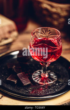 Glas rot Likör mit Schokolade auf Metall Fach Stockfoto