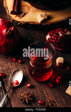 Schwarzer Tee in Arabisch Kaffee Glas mit frischem Granatapfel und einige Gewürze auf hölzernen Tisch Stockfoto