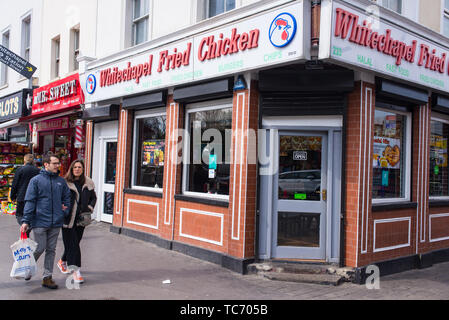 Whitechapel, London, England, UK - April 2019: Whitechapel Fried Chicken Shop mit Menschen zu Fuß in fornt auf der Whitechapel Road, Shadwell, London Stockfoto