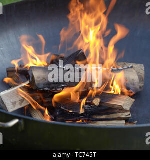 In der Nähe von blazing Logs von Holz in einen tragbaren Grill mit Fiery orange Flammen und gehackte Kindling unten Stockfoto