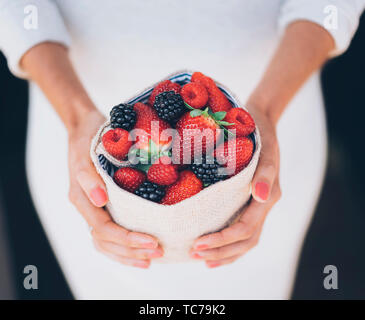 Gesunde und saftige Beeren Früchte in der Frau die Hände mit weißem Kleid Stockfoto