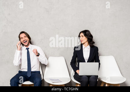 Attraktive Frau mit Laptop an der glücklichen Mann auf dem Smartphone suchen Stockfoto