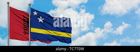 Albanien und Curacao Flagge im Wind gegen Weiße bewölkt blauer Himmel zusammen. Diplomatie Konzept, internationale Beziehungen. Stockfoto