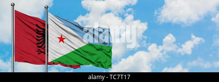 Albanien und Dschibuti Flagge im Wind gegen Weiße bewölkt blauer Himmel zusammen. Diplomatie Konzept, internationale Beziehungen. Stockfoto