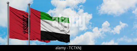 Albanien und der Vereinigten Arabischen Emirate Flagge im Wind gegen Weiße bewölkt blauer Himmel zusammen. Diplomatie Konzept, internationale Beziehungen. Stockfoto