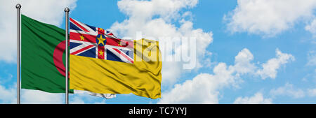 Algerien und Niue Flagge im Wind gegen Weiße bewölkt blauer Himmel zusammen. Diplomatie Konzept, internationale Beziehungen. Stockfoto