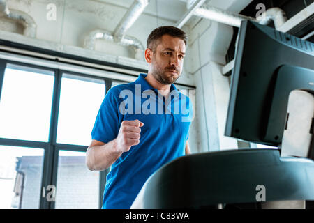 Schöner Mann auf Laufband im Fitnessstudio läuft Stockfoto