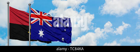 Angola und Australien Flagge im Wind gegen Weiße bewölkt blauer Himmel zusammen. Diplomatie Konzept, internationale Beziehungen. Stockfoto