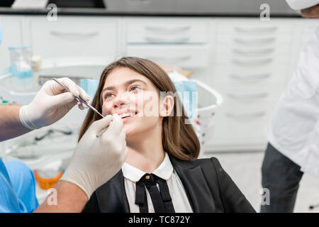Junge schöne Frau im Zahnarztstuhl an der Zahnklinik. Medizin, Gesundheit, Stomatologie Konzept. Zahnarzt Behandlung eines Patienten. Lächelnde Frau Stockfoto