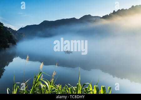 Nebel füllt Xiao Dongjiang 4 (Am frühen Morgen des Sommers, dicker Nebel durchdringt Xiao Dongjiang und in der Licht und Schatten auf den Sonnenaufgang, Fischer bereiten Sie Fisch.) Stockfoto