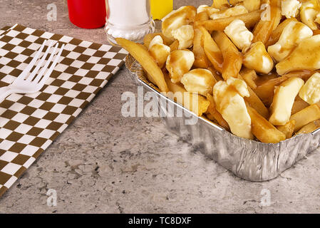 Poutine in einem takeout Container. Mit Pommes frites, Soße und Quark zubereitet. Kanadische Küche. Stockfoto