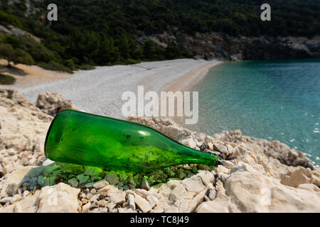 Leere Flasche liegend auf den Felsen am Strand in der Nähe von Lubenice (Cres, Kroatien) an einem sonnigen Tag im Frühjahr Stockfoto
