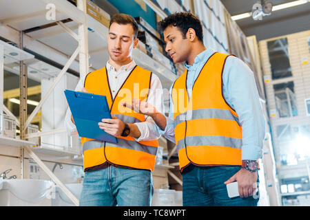 Multikulturelle Lagerarbeiter in Warnwesten in Sanitär Abteilung arbeiten Stockfoto