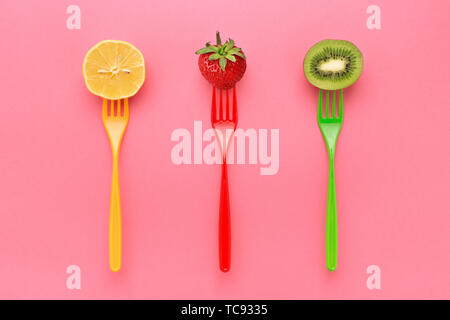 Straeberry Zitrone und Kiwi auf bunten Gabeln auf rosa Hintergrund saftige Farben des Sommers. Stockfoto