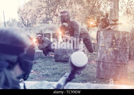 Weibliche paintball Spieler in voller Ausrüstung, die mit Gewehr im shootout auf dem Schlachtfeld Stockfoto