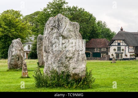 Steine der prähistorischen Steinkreis von Avebury mit dem Strohdach Village Pub, dem Red Lion, im Hintergrund. Stockfoto