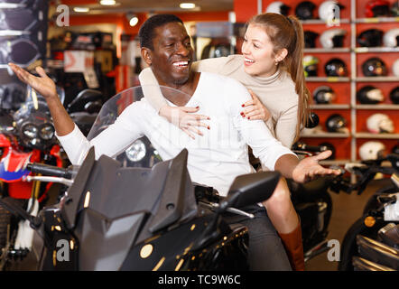 Glücklich lächelnde junge Paar mit Wahl in modernes Motorrad salon zufrieden Stockfoto