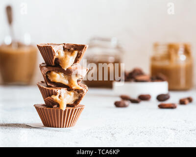 Stapel von vegane Schokolade Tassen mit Karamell auf weißen Tischplatte. Hausgemachte vegetarische Chocolate Caramel Cups mit rohem Kakao Schokolade. Ideen und Rezepte für gesunde Süßigkeiten und Desserts. Kopieren Sie Platz für Text Stockfoto