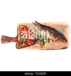 Croutons mit geröstetem Gemüse, Fisch und Zitrone, auf einem Holzbrett serviert. Isolieren Stockfoto