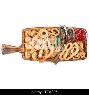 Gebratener Fisch, Zwiebelringe, Teig, Krabben, Muscheln in Sauce auf einem Holzbrett serviert. Isolieren Stockfoto