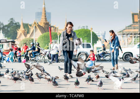 Ein junges kambodisches Mädchen füttert und jagt die Tauben vor dem Königspalast Phnom Penh Kambodscha. Stockfoto