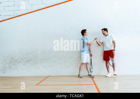 Die volle Länge der Squash Spieler Hände schütteln in vier-ummauerten Hof Stockfoto