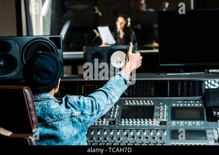 Selektiver Fokus der gemischten Rennen sound Hersteller zeigen Daumen bis zu Frau singen in Recording Studio Stockfoto