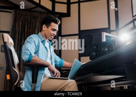 Lächelnd Mixed Race Sound Hersteller sitzen in Recording Studio und mit Laptop Stockfoto