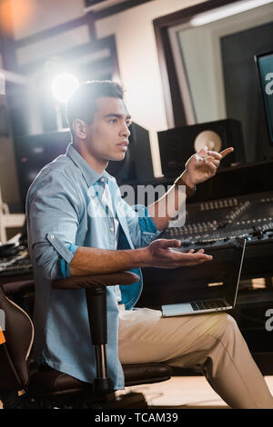 Ernsthafte Mixed Race Sound Hersteller Gestik beim Sitzen am Mischpult im Recording Studio Stockfoto