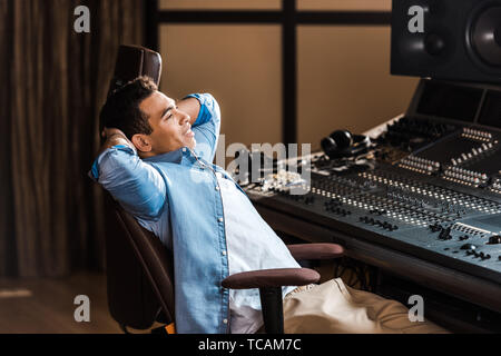 Schöner lächeln Mixed Race Sound Hersteller in Bürostuhl Ausruhen im Recording Studio Stockfoto
