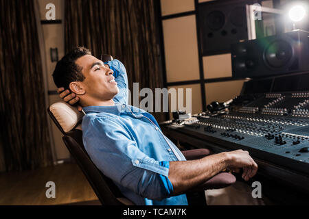 Lächelnd Mixed Race Sound Hersteller entspannen im Bürostuhl in Recording Studio Stockfoto