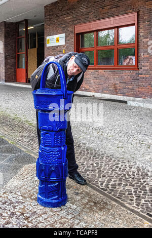 Älterer mann Getränke Wasser aus alten blauen Wasser Brunnen außerhalb ruhleben U-Bahnhof Westend, Berlin Stockfoto