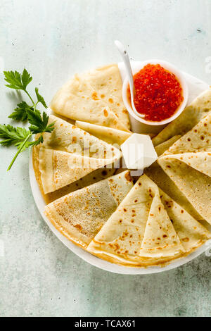 Die traditionellen russischen Pfannkuchen mit roter Kaviar und Butter auf dem weißen Tisch Stockfoto