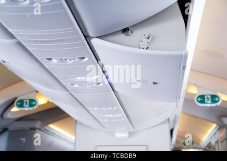 Geöffnet Flugzeug Storage (Tragen) und Blau service Licht neben. Und blurry green Notausgang Schild hinter sich. Stockfoto