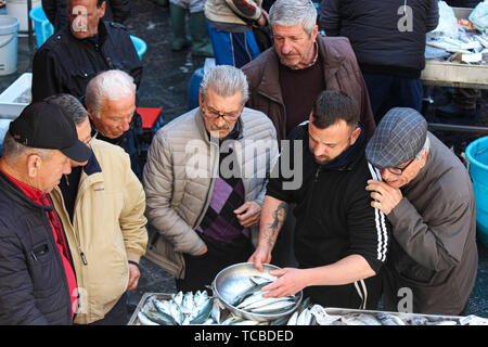 Catania, Sizilien, Italien - Apr 10 2019: fischhändler Verkauf frischer Fisch auf einem traditionellen Fischmarkt. Gruppe von alten Männern Käufer beobachten und Beratung. Beliebte Attraktion. Stockfoto