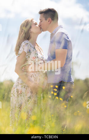 Junge glücklich schwanger Paar in Liebe Hände halten, entspannen in der Wiese. Stockfoto