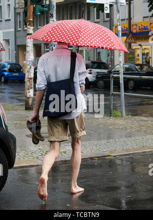 Berlin, Deutschland. 06 Juni, 2019. Ein Mann barfuß über eine Straße im Regen. Credit: Paul Zinken/dpa/Alamy leben Nachrichten Stockfoto