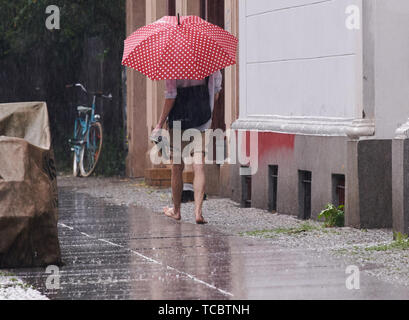 Berlin, Deutschland. 06 Juni, 2019. Ein Mann barfuß über eine Straße im Regen. Credit: Paul Zinken/dpa/Alamy leben Nachrichten Stockfoto