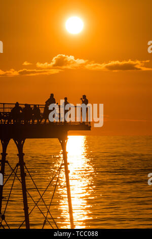 Aberystwyth Wales UK, Donnerstag, 06. Juni 2019 Menschen mit einem Drink auf der Pier auf einem herrlich warmen und klaren Sommer Abend in Aberystwyth auf der West Wales Küste, am Ende eines Tag intensiver Regen und Sonnenschein Foto Keith Morris/Alamy leben Nachrichten Stockfoto