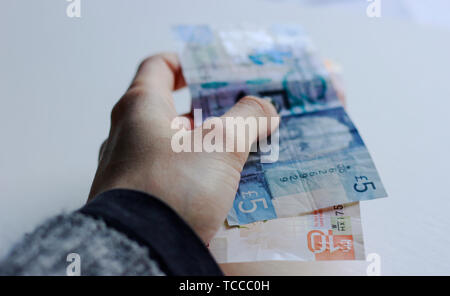 Bank von Schottland Noten, Noten des Pfund Sterling, Mai 2019, UK. Frau mit Pfund Papier schottische Banknoten über isolierte Hintergrund. Stockfoto